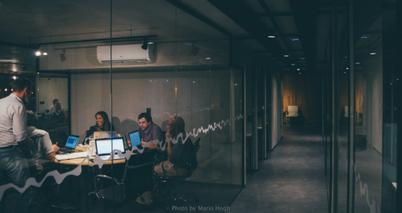 Business professionals using phones and laptops while working together around a table.