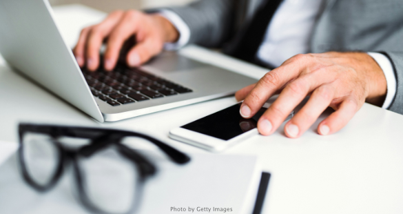 Business professional reviewing documents beside a laptop and mobile phone.
