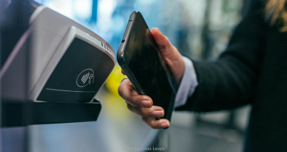 Person presenting a smartphone at the entrance to a transport or event service.